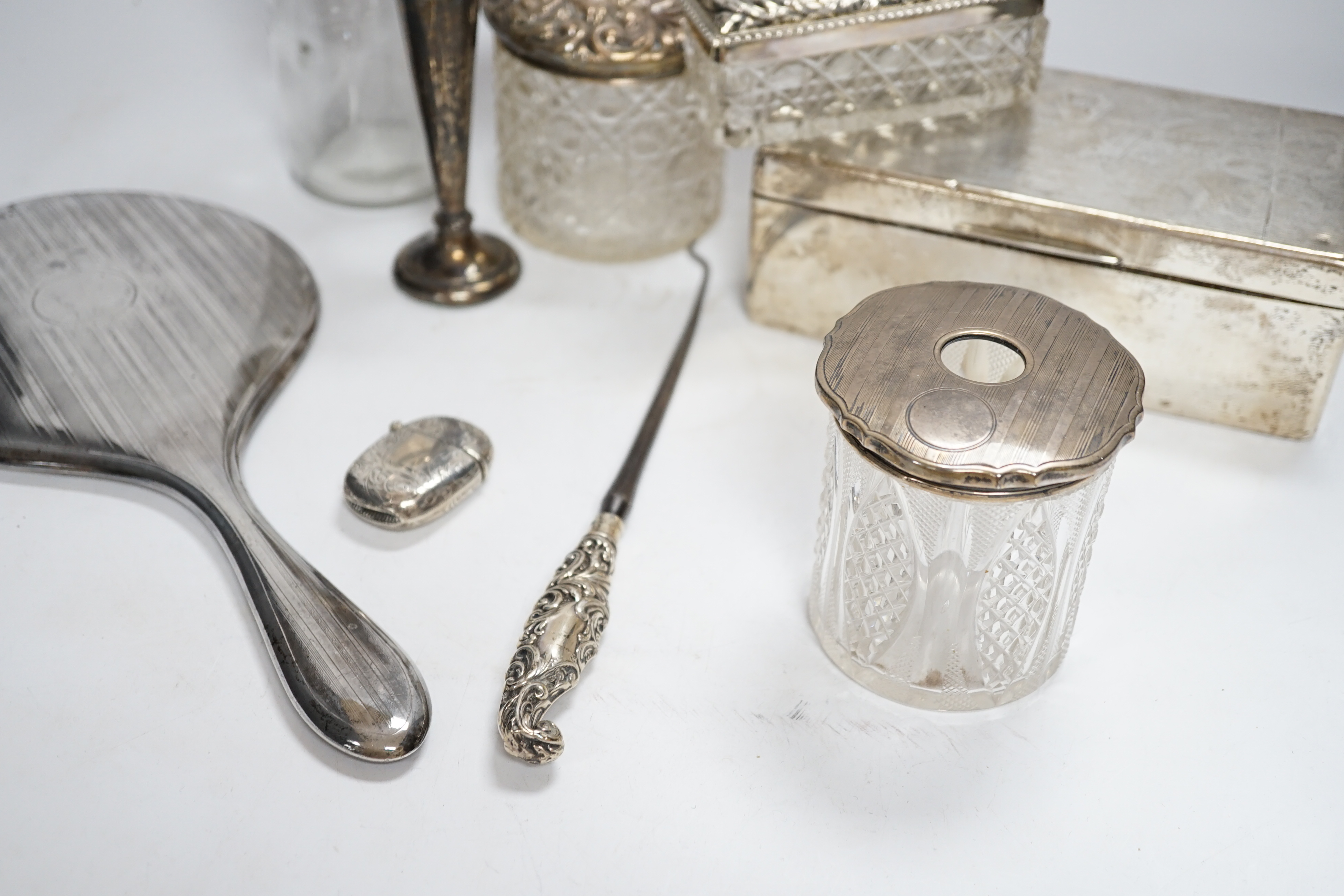 Sundry small silver including a silver mounted cigarette box, four assorted mounted glass toilet jars, a vesta case, button hook, hand mirror and trumpet vase.